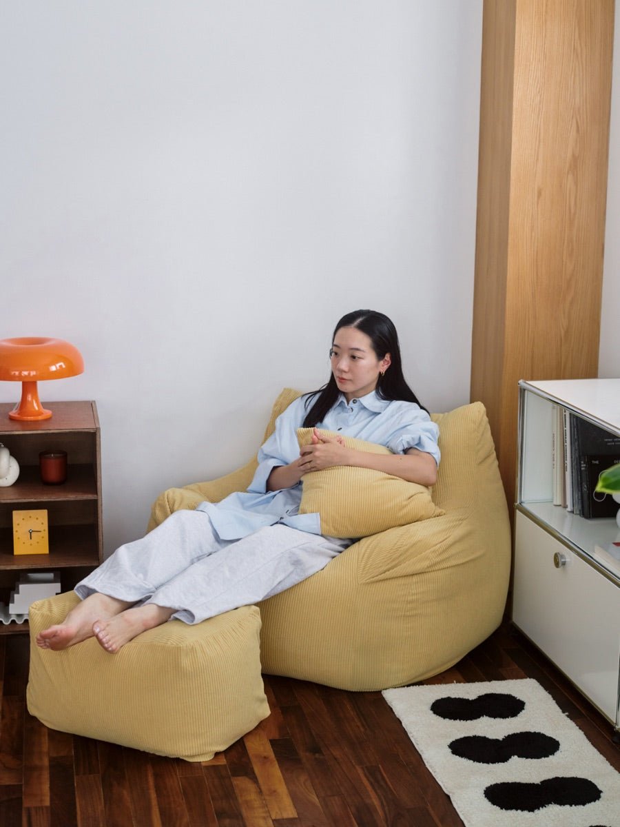 イエローのLOOSYとオットマンに脚を伸ばしてくつろぐ女性