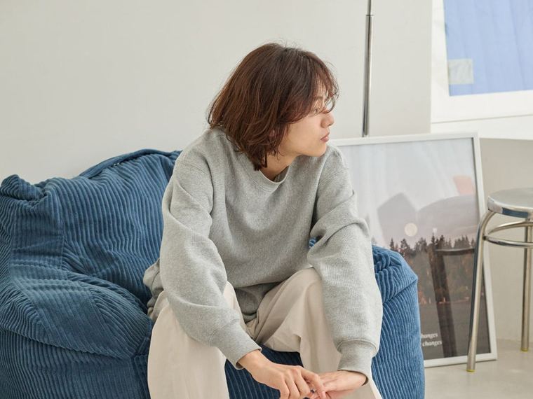 ブルーのLOOSYに腰掛け、身体を起こしている女性