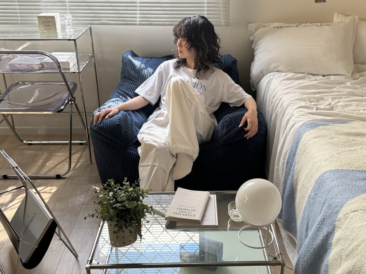 ネイビーの1人掛けに座って、ベッド脇でくつろぐ