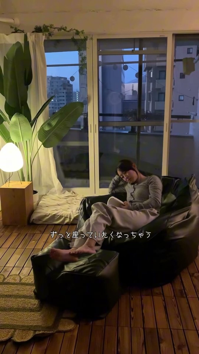 背中と片肘を預け、黒いLOOSYで本を読む人